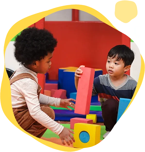 Two children playing with blocks in a room.