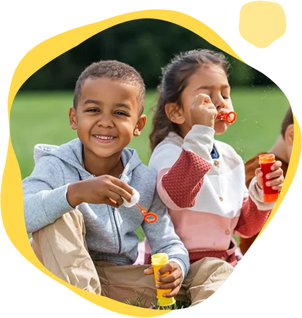 Two children are sitting on a bench and eating.