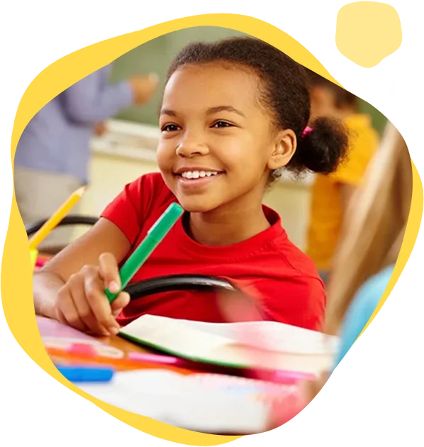 A young girl holding a green pencil and smiling.