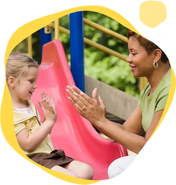 A woman and child on slide at park.