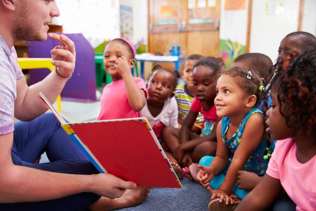 A group of children sitting in front of an adult.