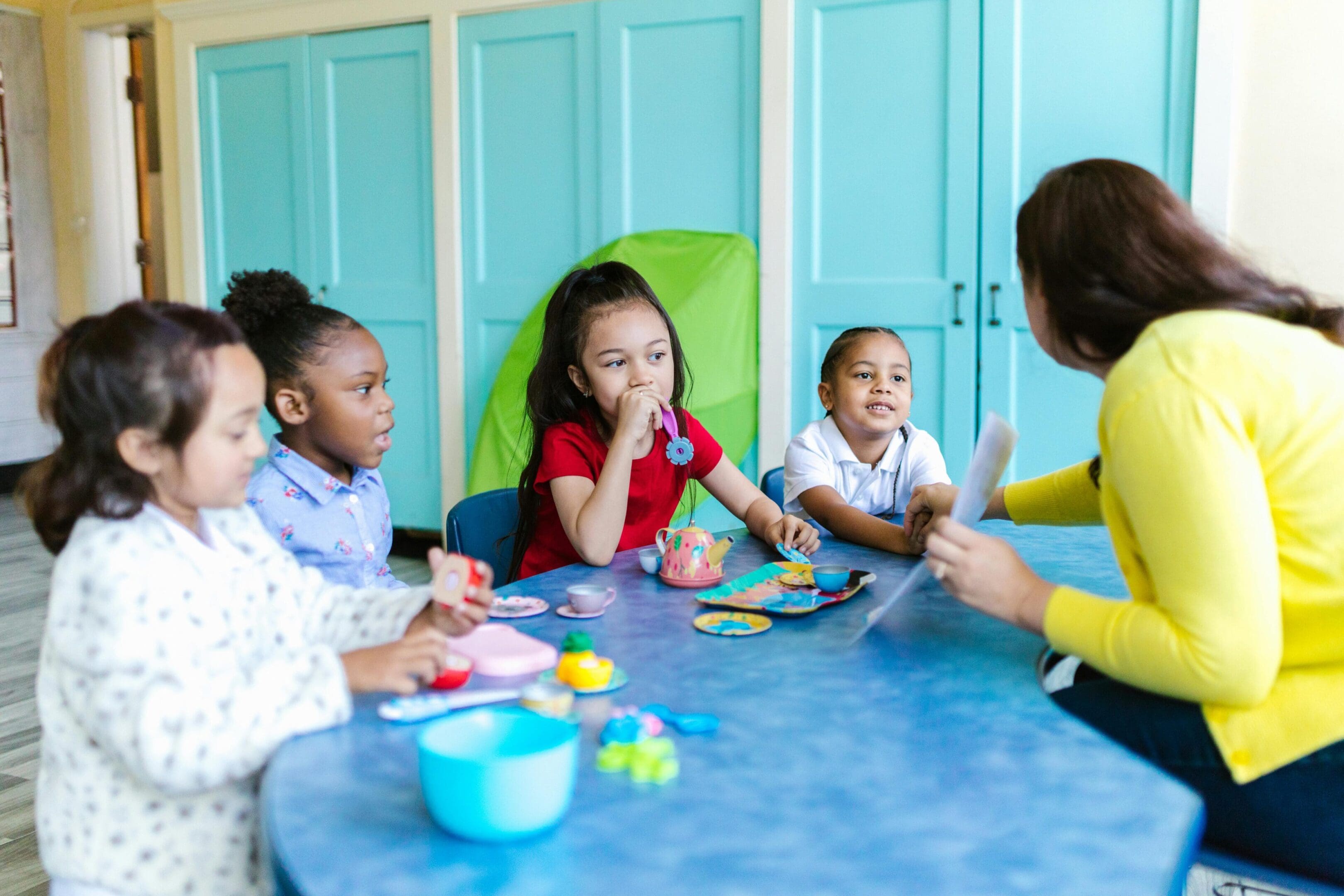 A group of children sitting at a table with an adult.